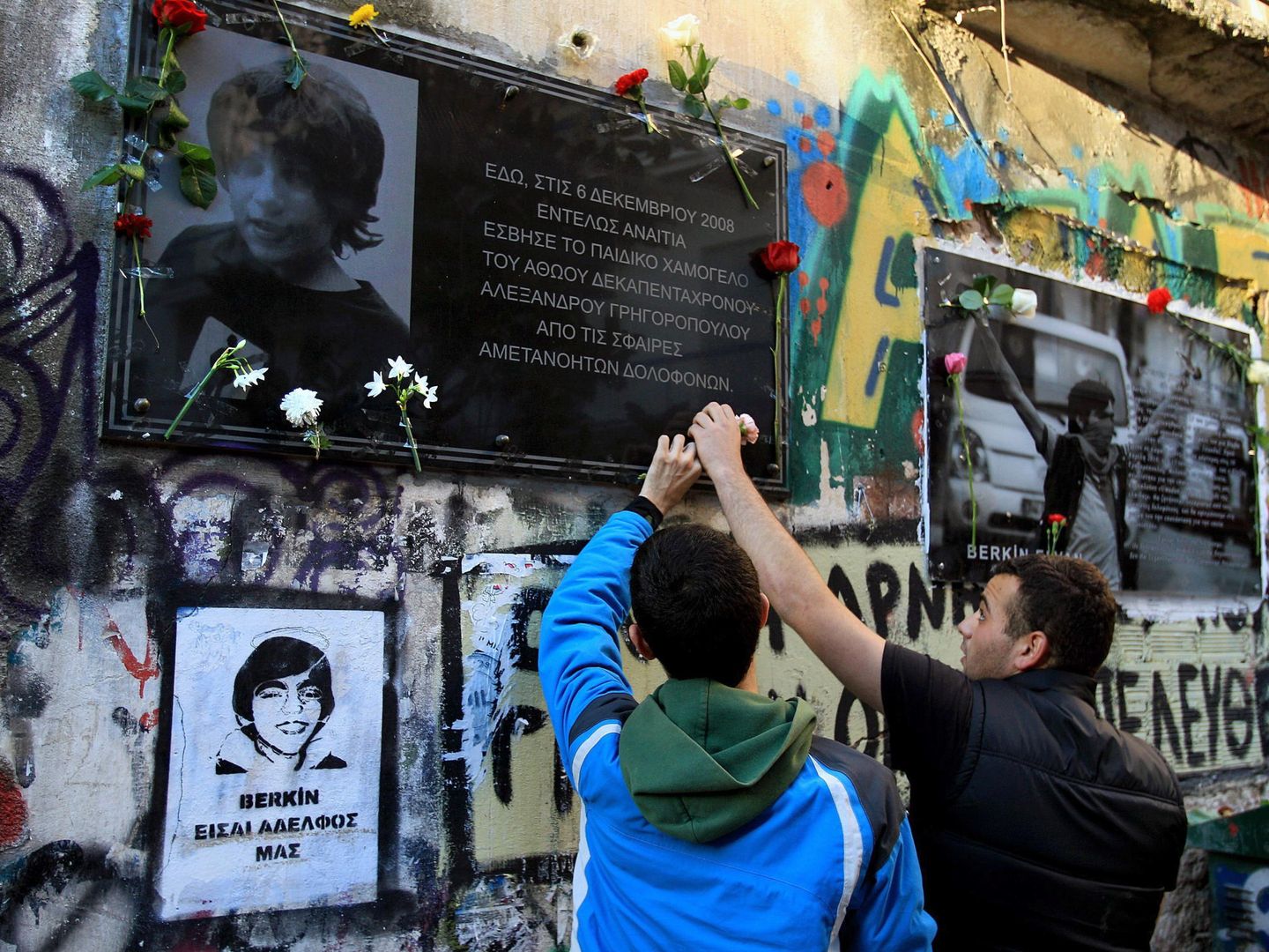 Dos estudiantes dejan flores en el lugar de la muerte del adolescente Alexis Grigoropoulos, abatido por la policía en 2008 en Exarchia. (EFE)