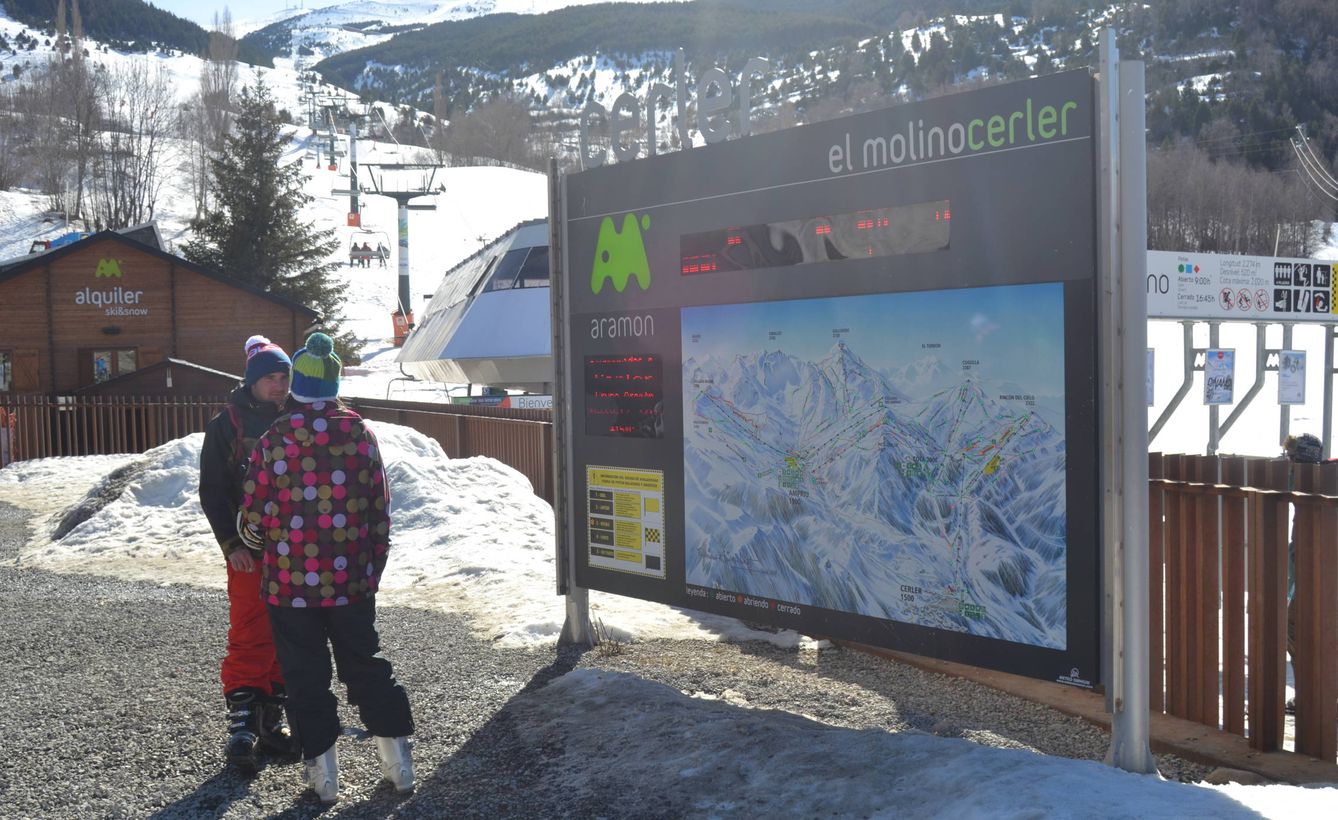 Dos esquiadores en la zona de El Molino delante de un plano de las pistas que sirve de perfecta orientación para un viaje distinto por Cerler.