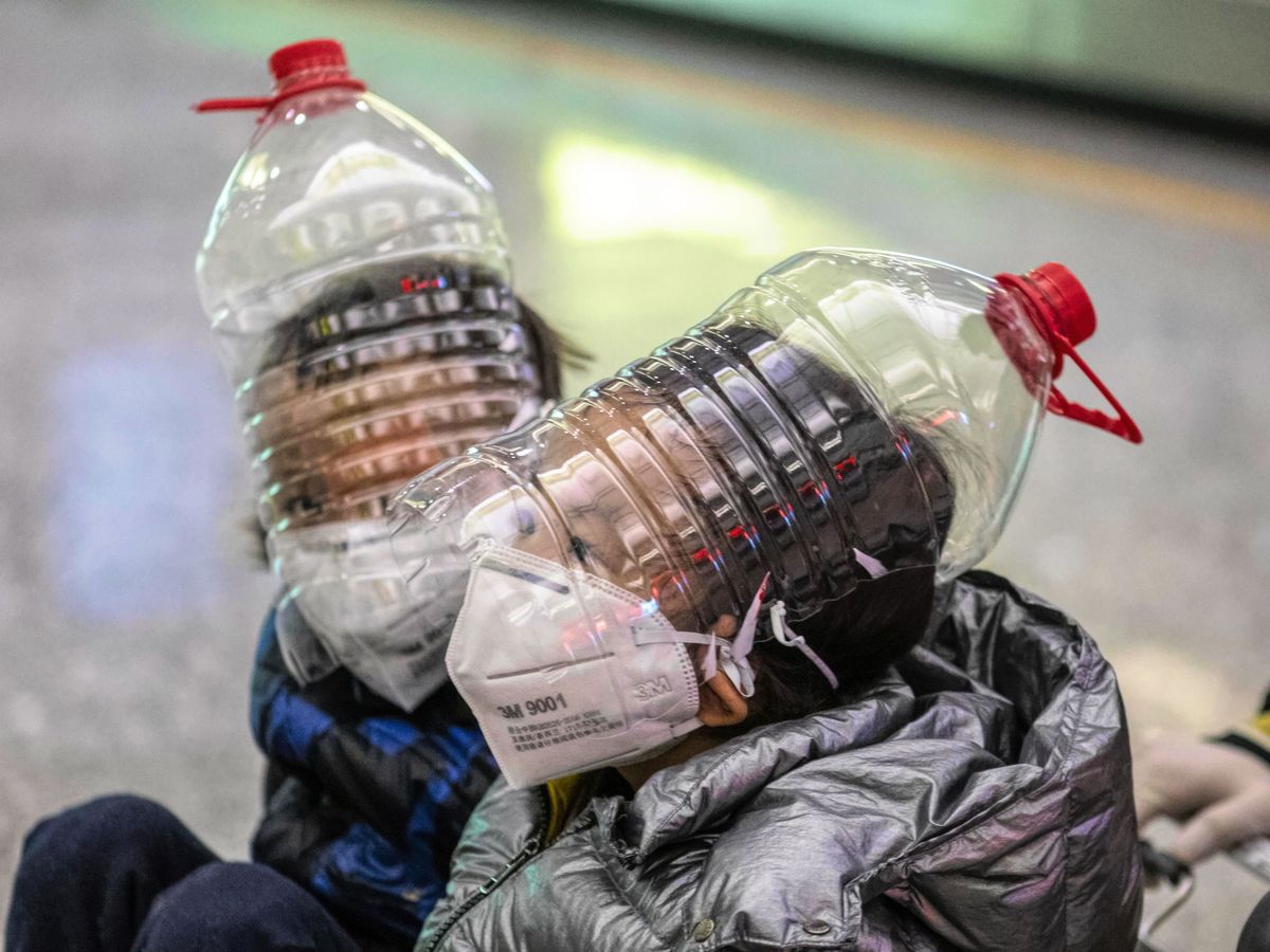 Foto: Dos niños se 'protegen' del coronavirus con botellas de plástico. (EFE)