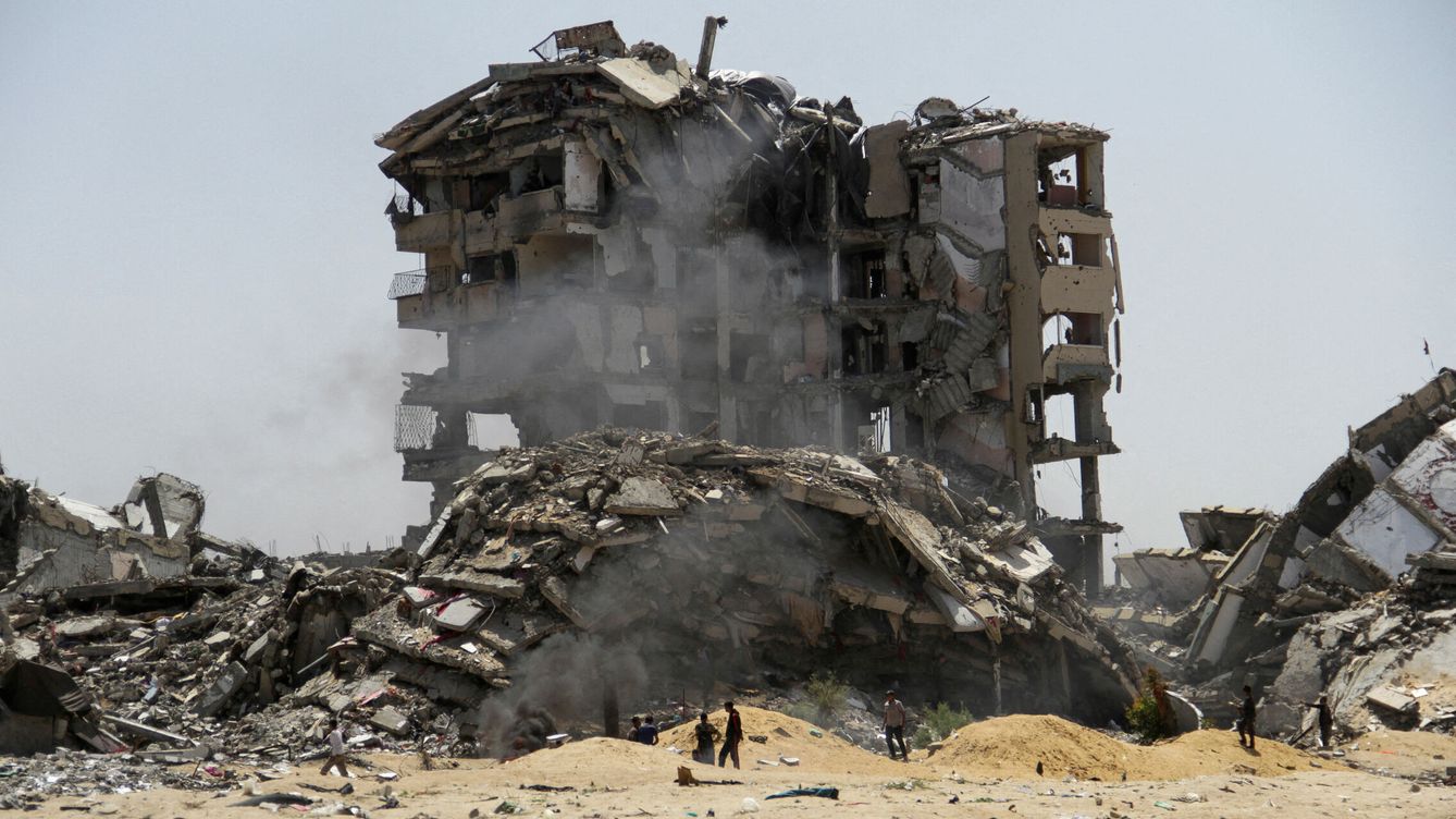 Foto: Varios palestinos paseando frente a las ruinas de un edificio por los ataques en Gaza. (Reuters/Mahmoud Issa)