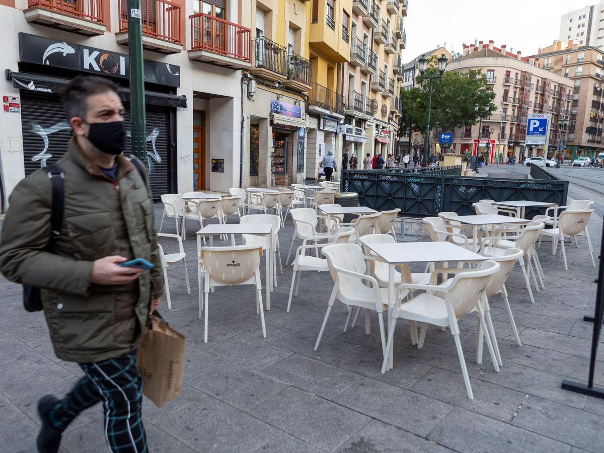 Foto: Un hombre camina junto a una terraza vacía el pasado viernes en Zaragoza. (EFE)