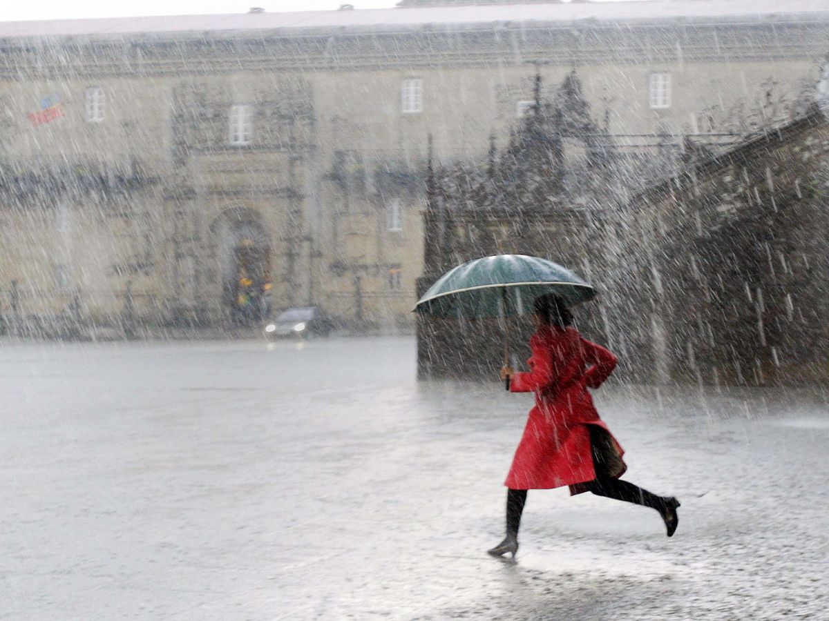 Foto: Una mujer corre bajo la lluvia en Santiago de Compostela. (Efe)