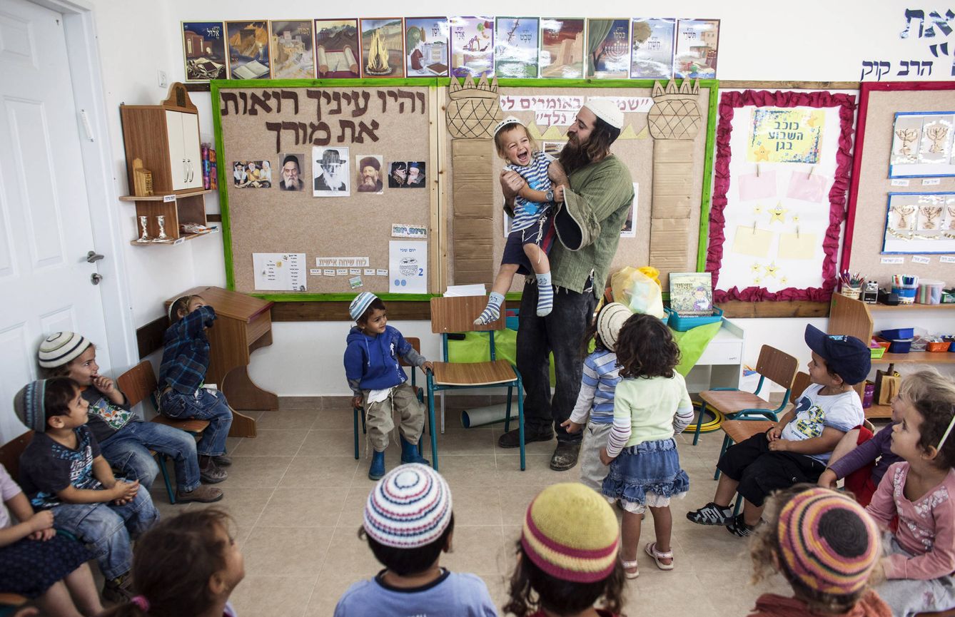 Natanel, un profesor, juega con un niño en la colonia de Havat Gilad, al sur de Nablús, en Cisjordania (Reuters).