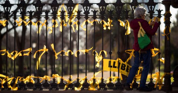 Foto: Una mujer coloca lazos amarillos en la verja del Pac de la Ciutadella, en el Paseo de Lluís Companys. (EFE)