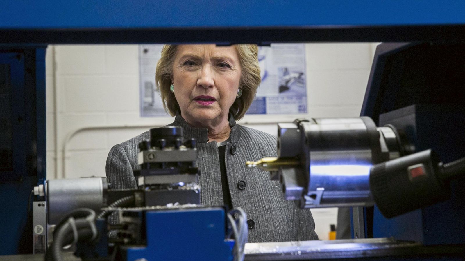 Foto: Clinton observa cómo funciona una máquina durante una visita al New Hampshire Technical Institute Community College (Reuters). 