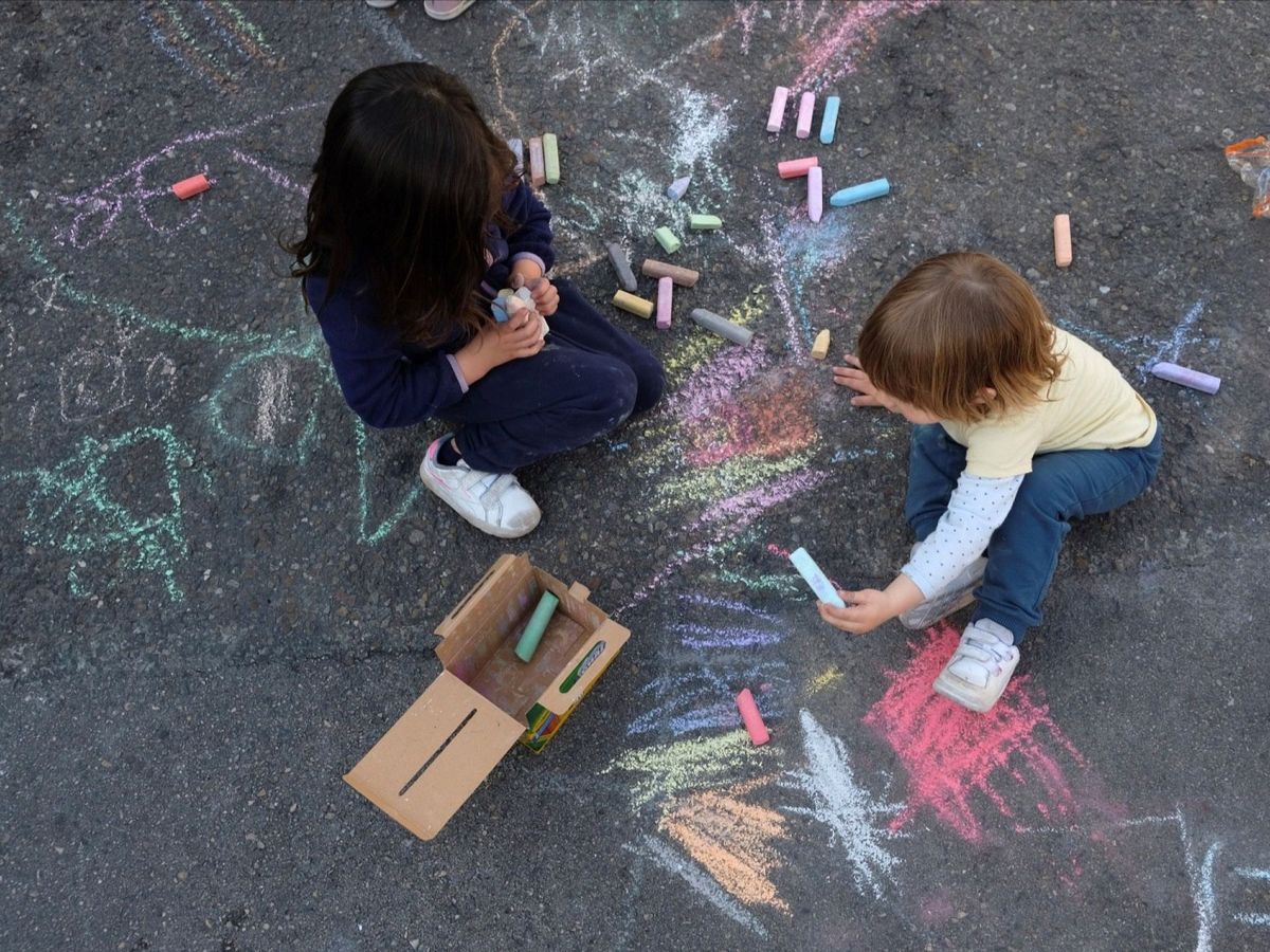 Foto: Dos niños juegan sobre el asfalto de la calle junto al colegio Asunción Rincón, en Madrid. (EFE)
