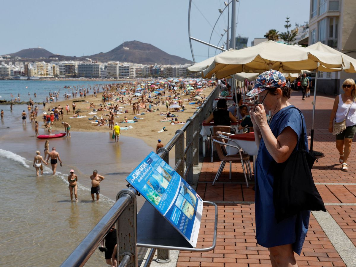 Foto: Una mujer extranjera observando un mapa en la playa de Las Canteras, en Canarias. (REUTERS/Borja Suarez)