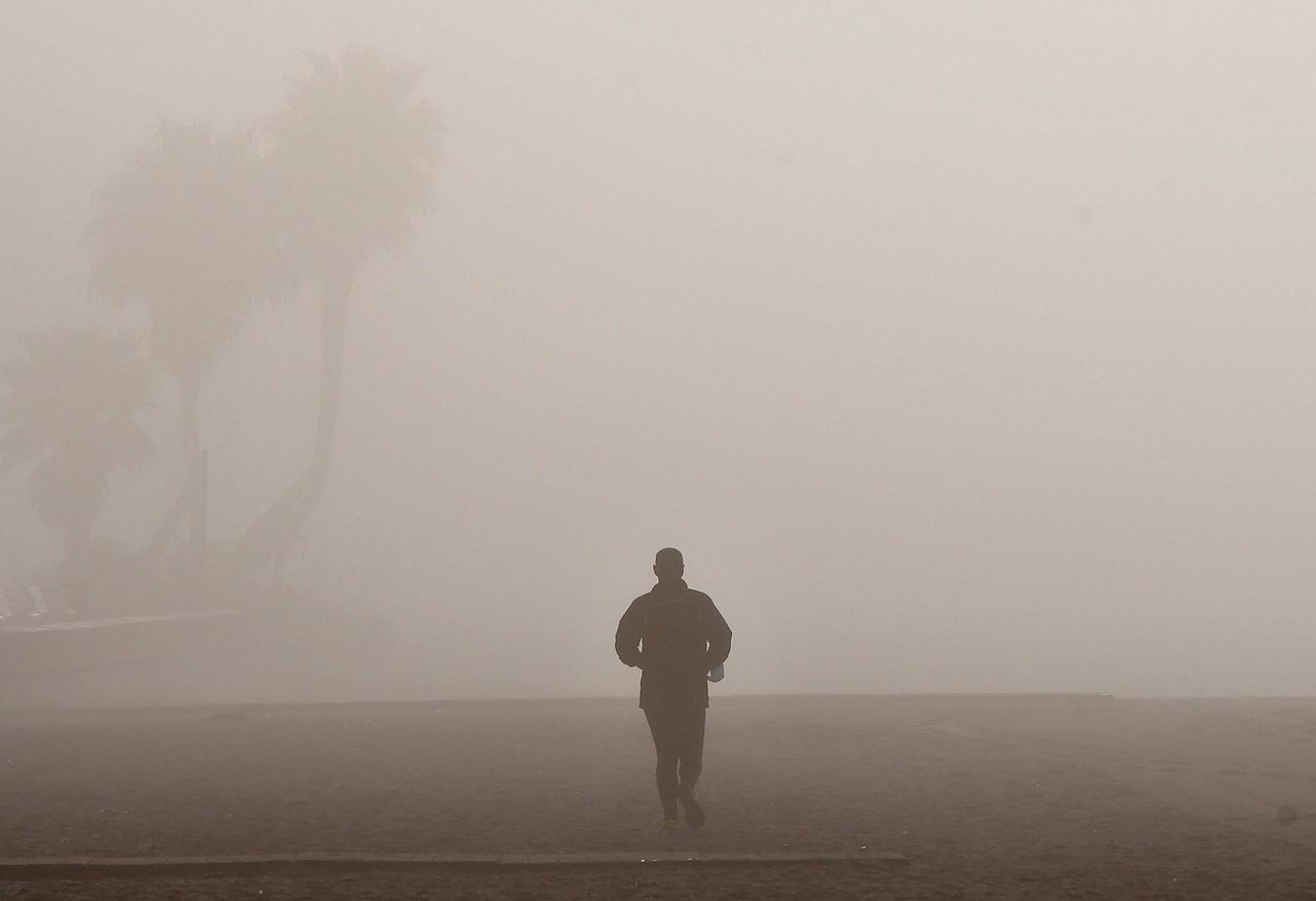 Un hombre corriendo con niebla. (EFE/Carlos Barba)