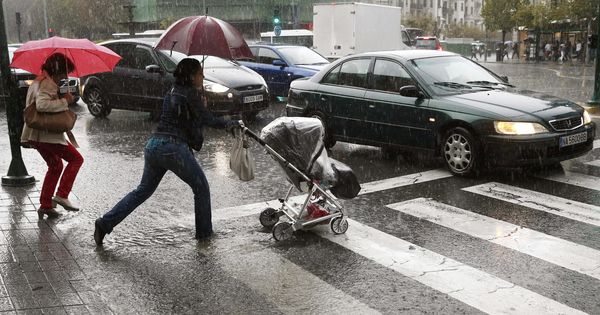 Foto: Dos personas pasan por un paso de peatones en Pamplona durante un día lluvioso. (EFE)