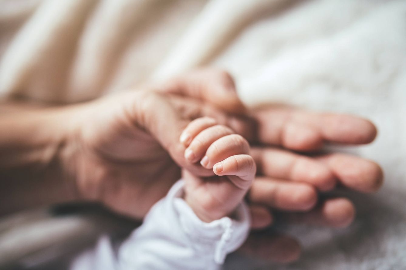 Placer al acariciar la mano de un bebé. (iStock)