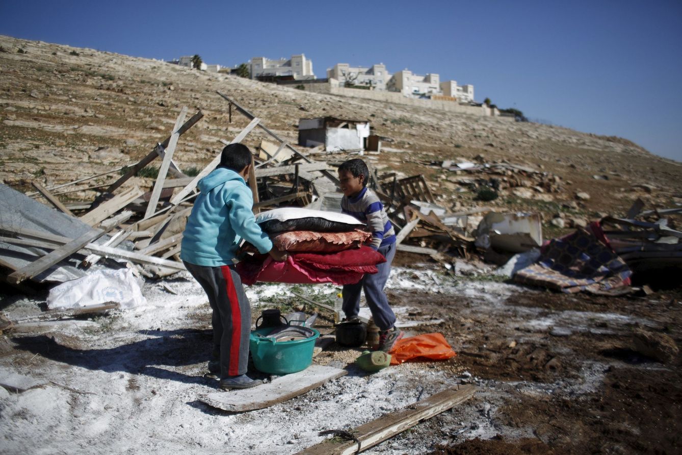 Niños palestinos cargan con sus pertenencias tras la demolición de su vivienda ante el asentamiento de Maale Adumim, cerca de Jerusalén. (Reuters)