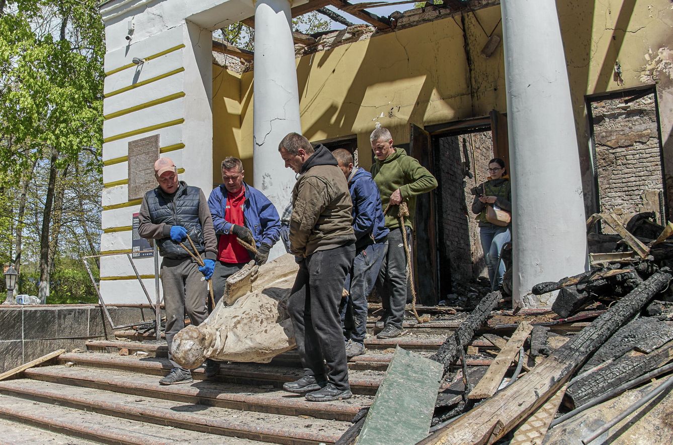 Civiles ucranianos tratan de salvar una estatua dañada por la invasión rusa. (EFE)