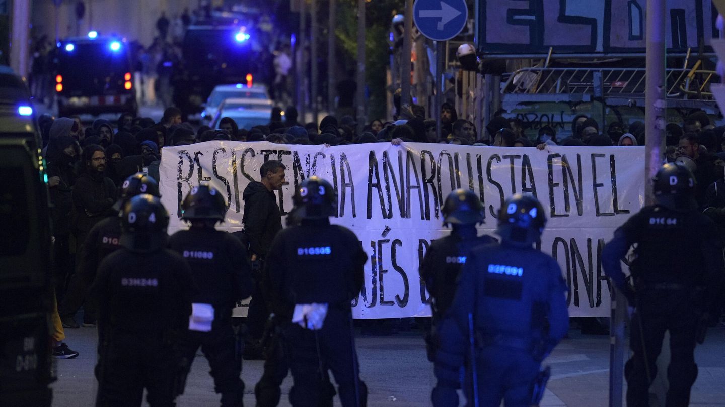 Mossos d'Esquadra vigilan a varios manifestantes simpatizantes de los okupas de la Bonanova. (EFE/Alejandro García) 