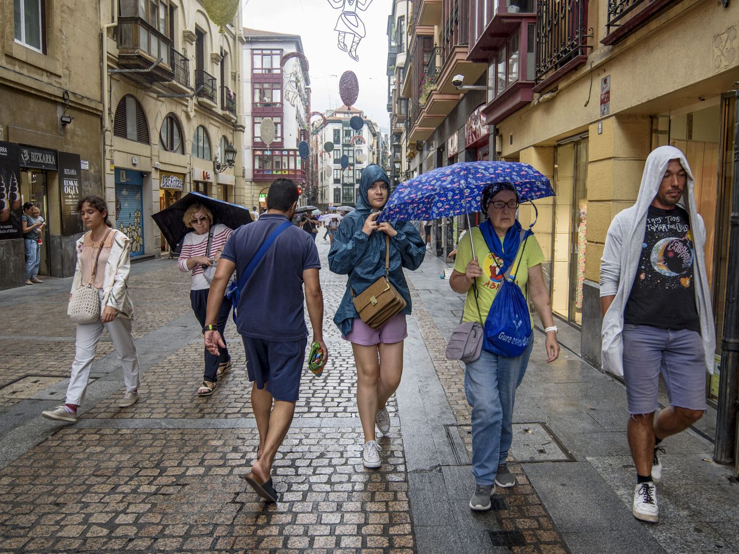 Viandantes se protegen de la lluvia en Bilbao este viernes. (EFE/Javier Zorrilla) 