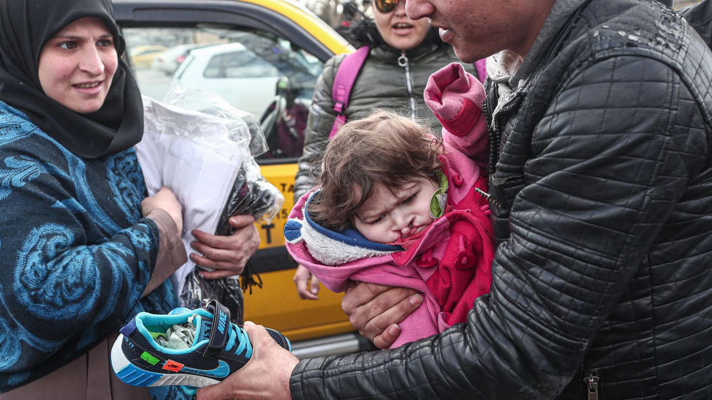 Un refugiado sirio porta a su hija de un año mientras trata de distribuir zapatos como artículo de ayuda en Turquía. (EFE)