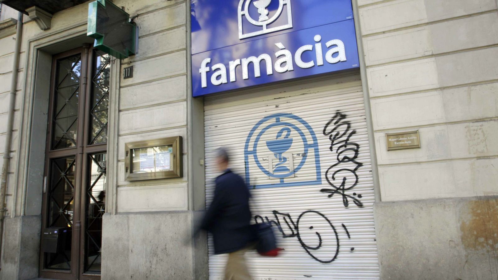 Foto: Una persona camina ante la fachada de una farmacia cerrada en el centro de Barcelona. (Efe) 