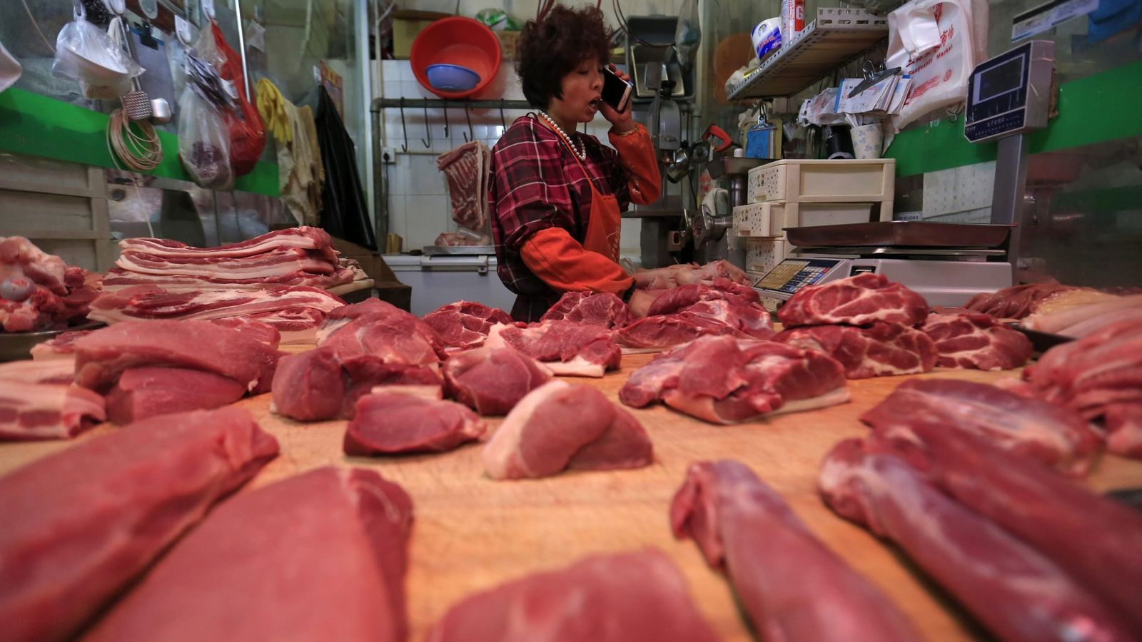Foto: Una vendedora habla por teléfono mientras cuida su carnicería en un mercado. (EFE)