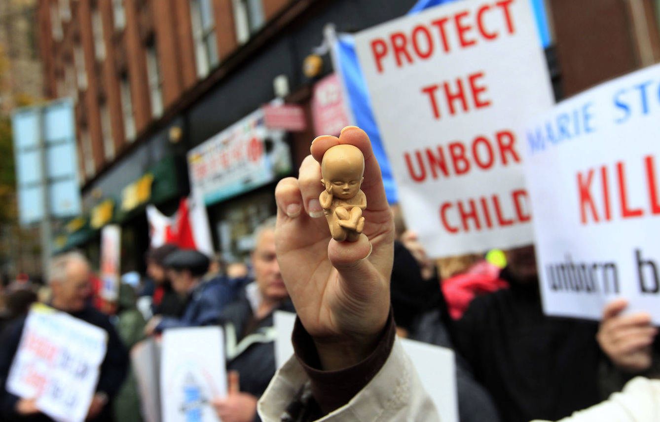 Una manifestante antiabortista sostiene un muñeco de un feto frente a una clínica de Belfast. (Reuters)