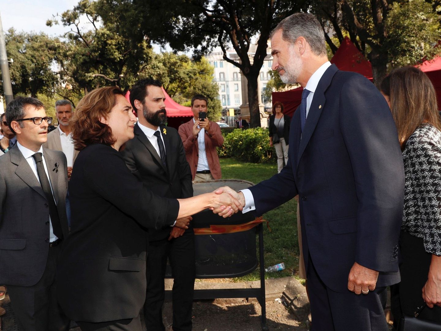 El Rey Felipe VI saluda a la alcaldesa de Barcelona, Ada Colau, durante los actos de homenaje. (EFE)