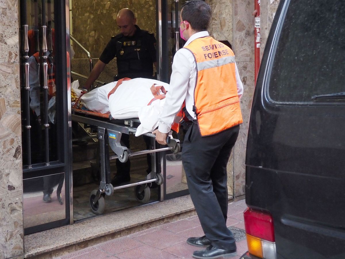 Foto: Operarios de los servicios funerarios sacan un cadáver de la dos viviendas de Valladolid. (EFE/Nacho Gallego)
