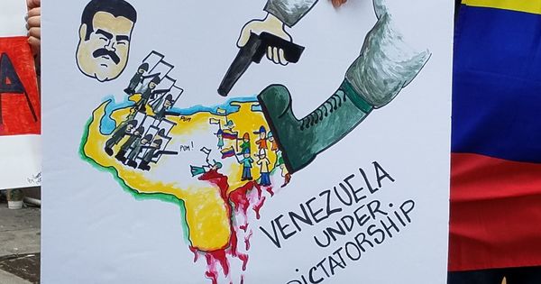 Foto: Una persona sostiene un cartel durante una manifestación de venezolanos frente al consulado de su país en Nueva York. (EFE)