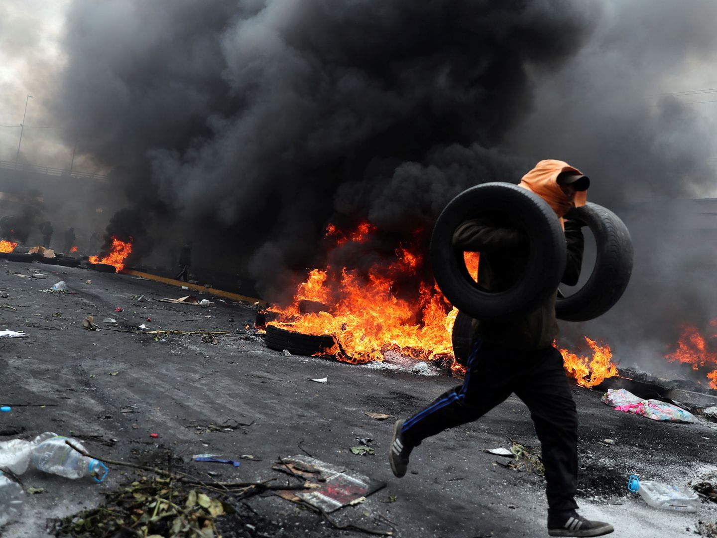 Un manifestante sostiene neumáticos mientras corre durante la protesta. (Reuters)