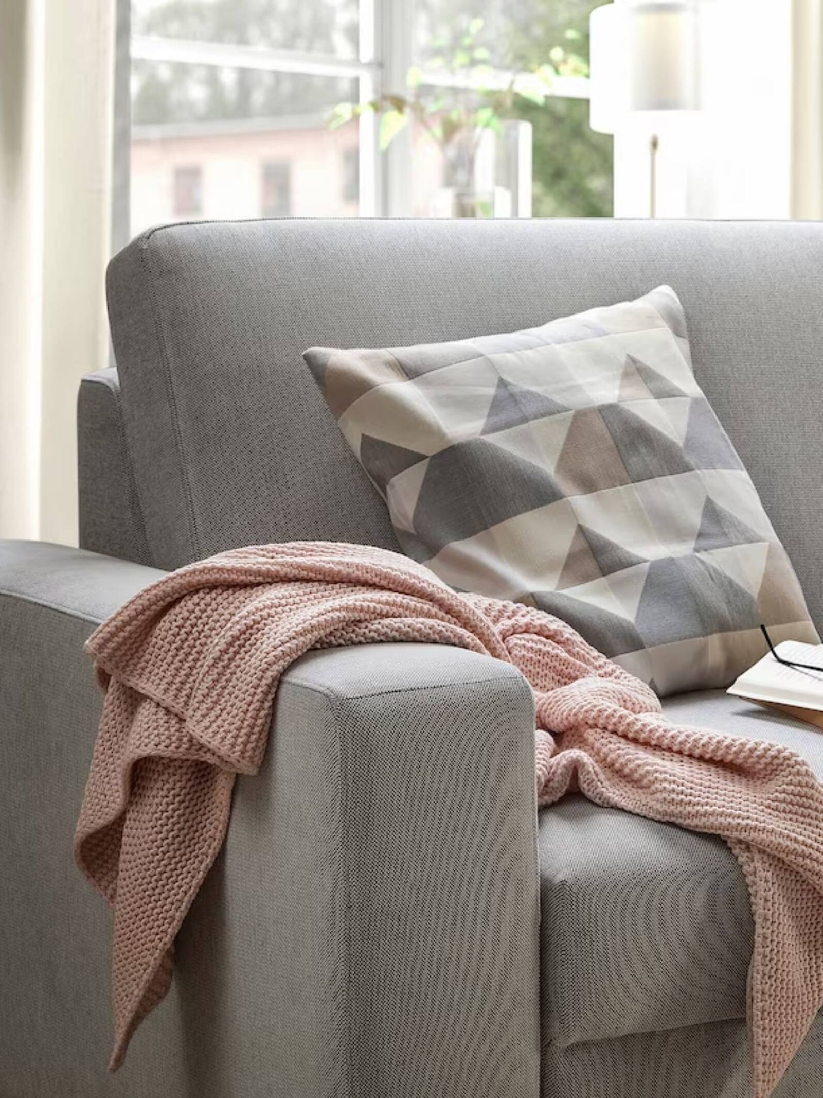 Un cojín en tonos tierra sobre un sofá de color gris. (Cortesía/Ikea)