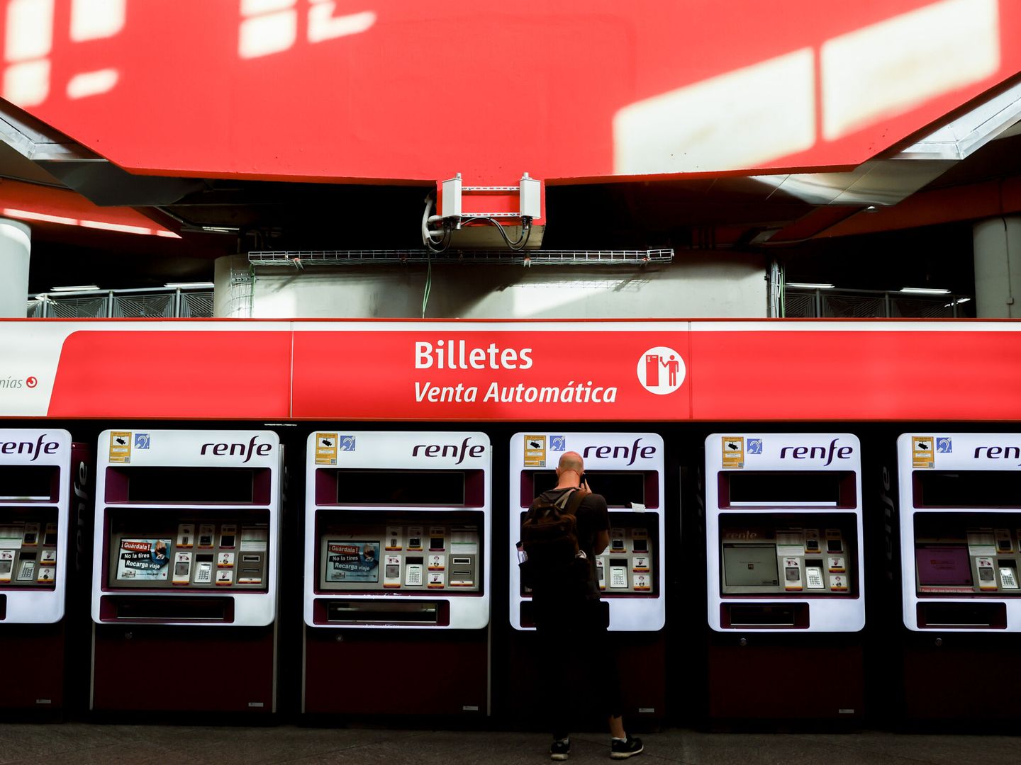 Viajeros gestionan la compra de sus abonos en máquinas expendedoras de billetes en una estación de Cercanías de Madrid. (EFE/Mariscal)