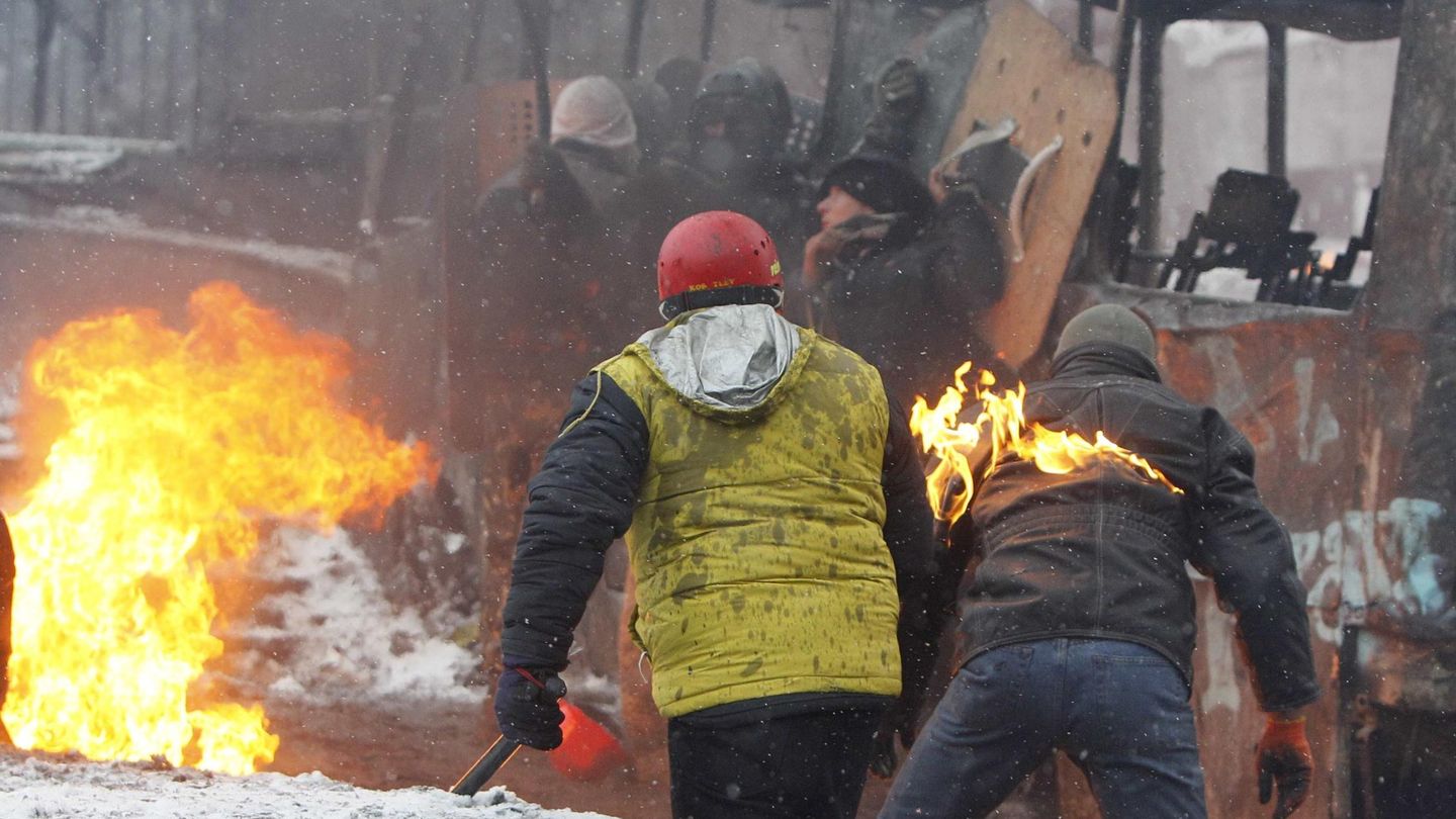 Manifestantes se protegen tras un autobús quemado en Kiev (Reuters).