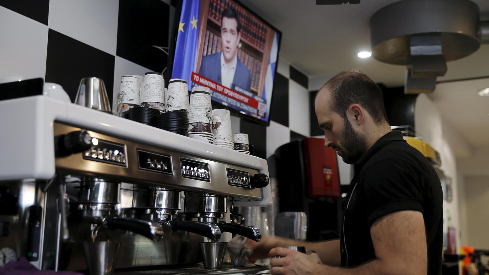 Foto: Un camarero escucha la intervención televisiva de Alexis Tsipras. (Reuters)