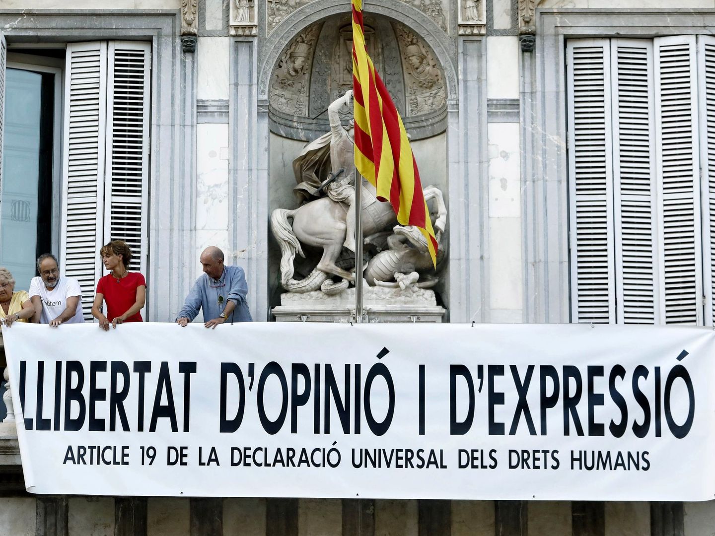 Lluís Llach (d), Antonio Baños (2i) y Silvia Bel (3i) colocan una pancarta en la sede de la Generalitat. (EFE)