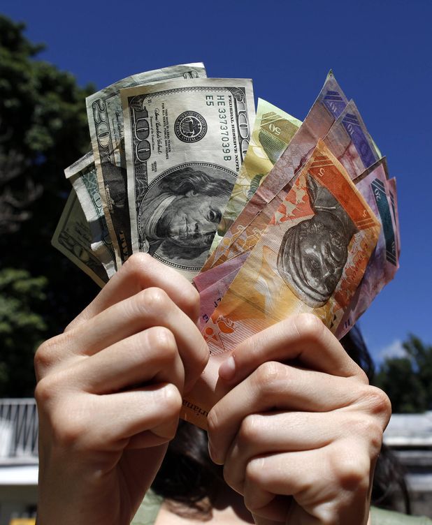 Una mujer sostiene varios billetes de dólar y de bolívar. (EFE)