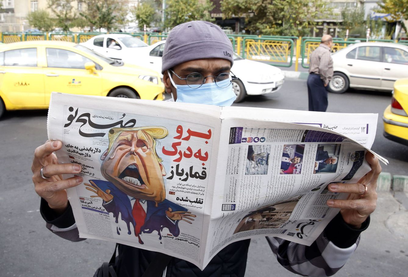 Un hombre lee la portada del periódico iraní 'Sobhe Nou', con una caricatura de Trump. (EFE)