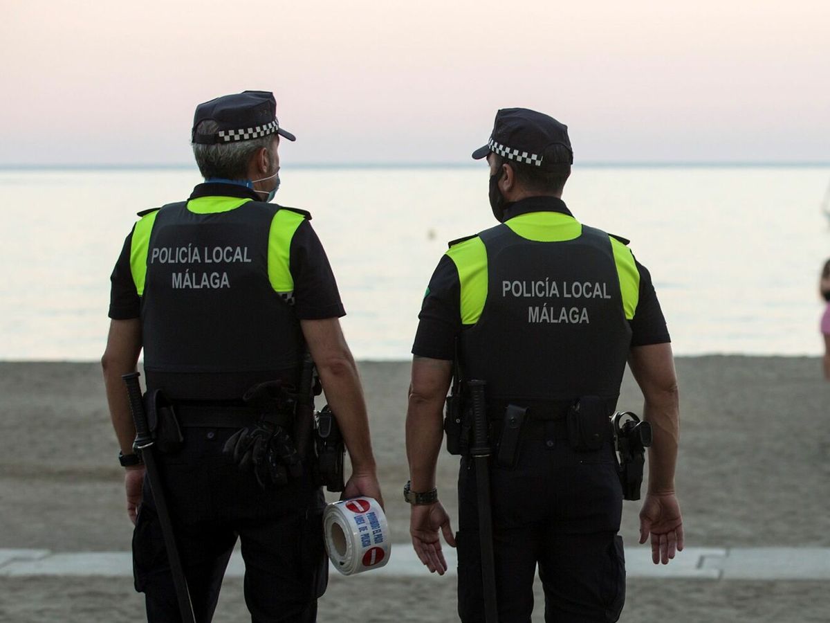 Foto: Miembros de la Policía Local de Málaga esperan a que se desaloje la playa de La Malagueta