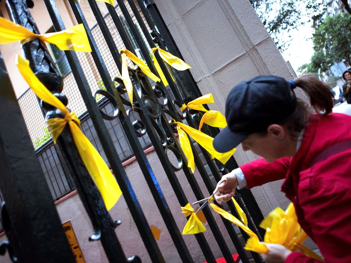 Foto: Uno de los miembros de los Grupos de Defensa y Resistencia retira los lazos amarillos en Barcelona en 2018. (EFE/Enric Foncuberta)