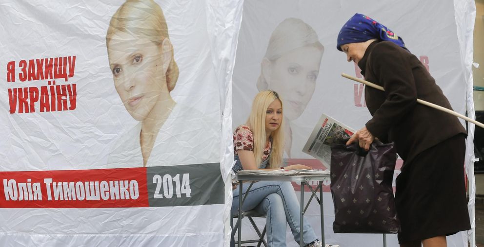 Una mujer recoge propaganda electoral de la candidatura de Timoshenko. (Efe)