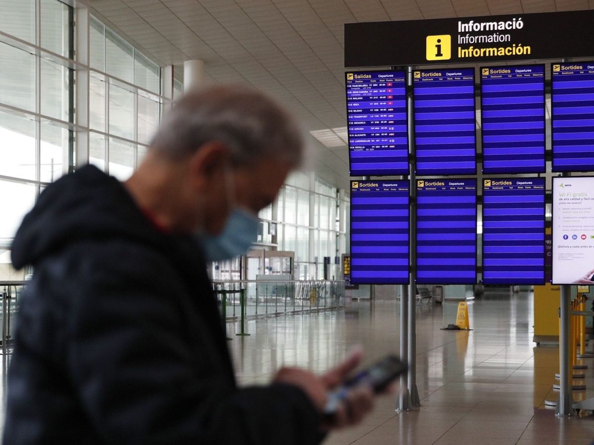 Foto: Un pasajero ante los paneles de información del Aeropuerto de Barcelona-El Prat  este lunes (EFE)