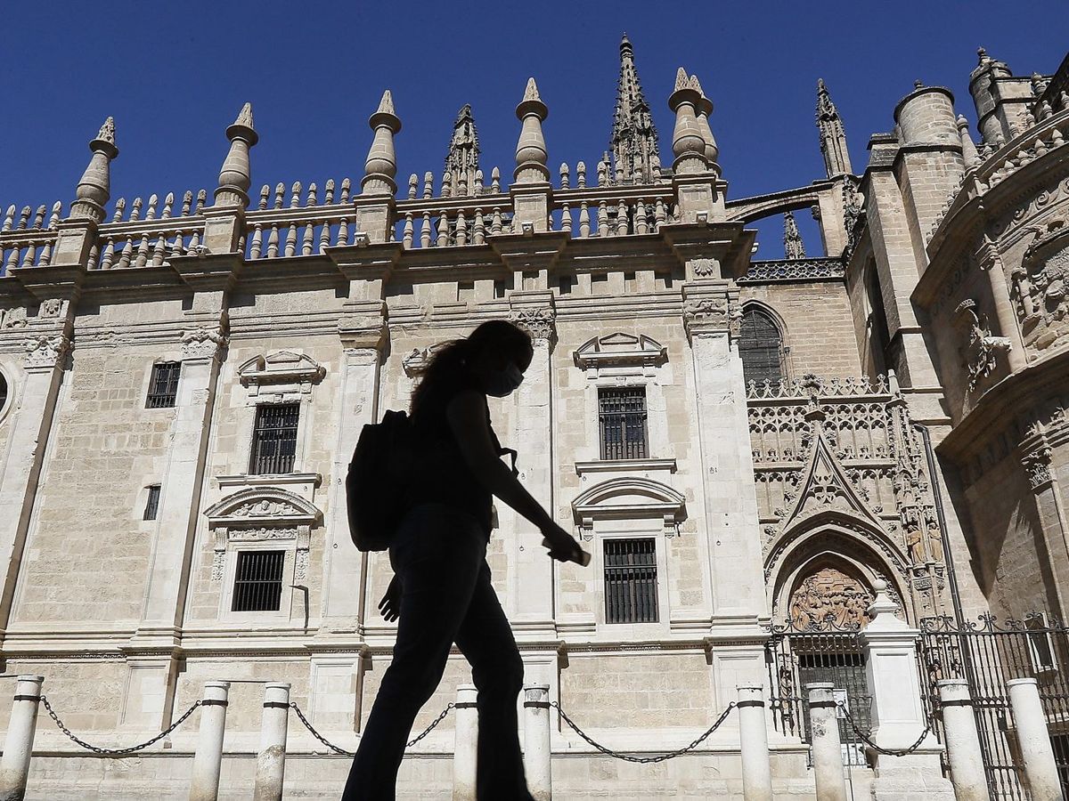 Foto: Una mujer camina delante de la Catedral de Sevilla. (EFE) 