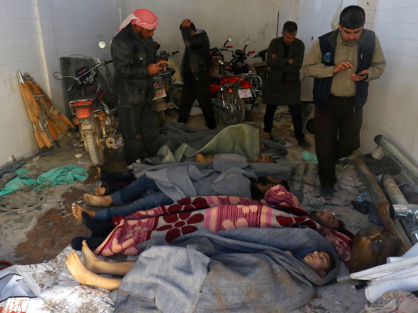 Varios hombres examinan los cadáveres de las víctimas del ataque químico del 4 de abril. (Reuters)