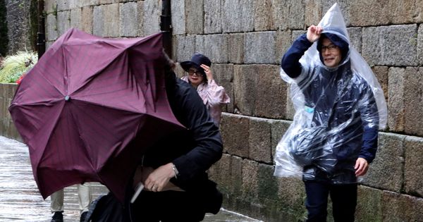 Foto: Turistas japoneses, luchando por no perder sus paraguas este domingo en Santiago de Compostela. (EFE)