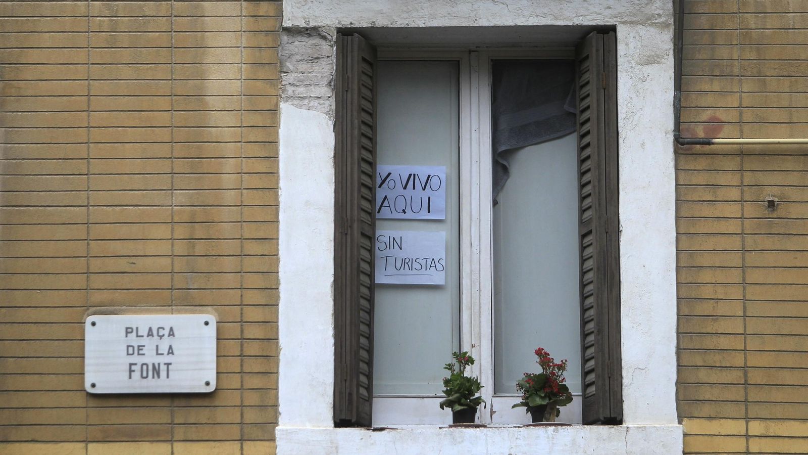 Foto: Un cartel en la ventana de un piso del barrio de La Barcelona avisa a los turistas de que se trata de una vivienda particular y no de un apartamento turístico. (EFE)