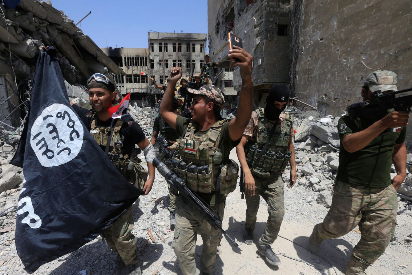 Efectivos del Ejército iraquí celebran la caída de Mosul con una bandera del Estado Islámico. (Reuters)