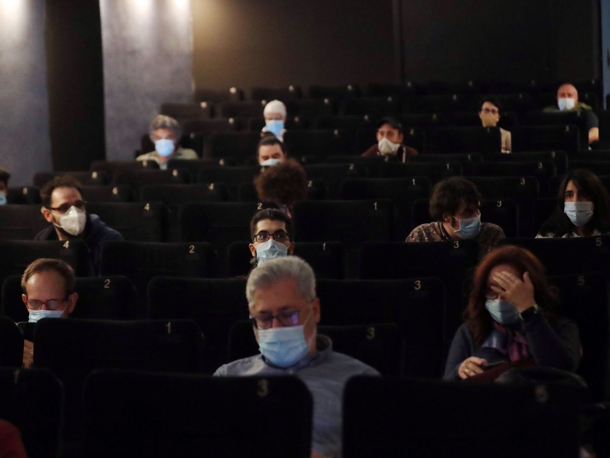 Foto: Varios espectadores ataviados con mascarillas asisten a la proyección de una película tras la reapertura del cine Renoir de Plaza de España, este viernes. (EFE) 