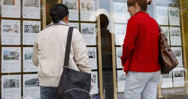 Foto: Dos jóvenes miran los carteles de viviendas en venta de una inmobiliaria. (EFE)