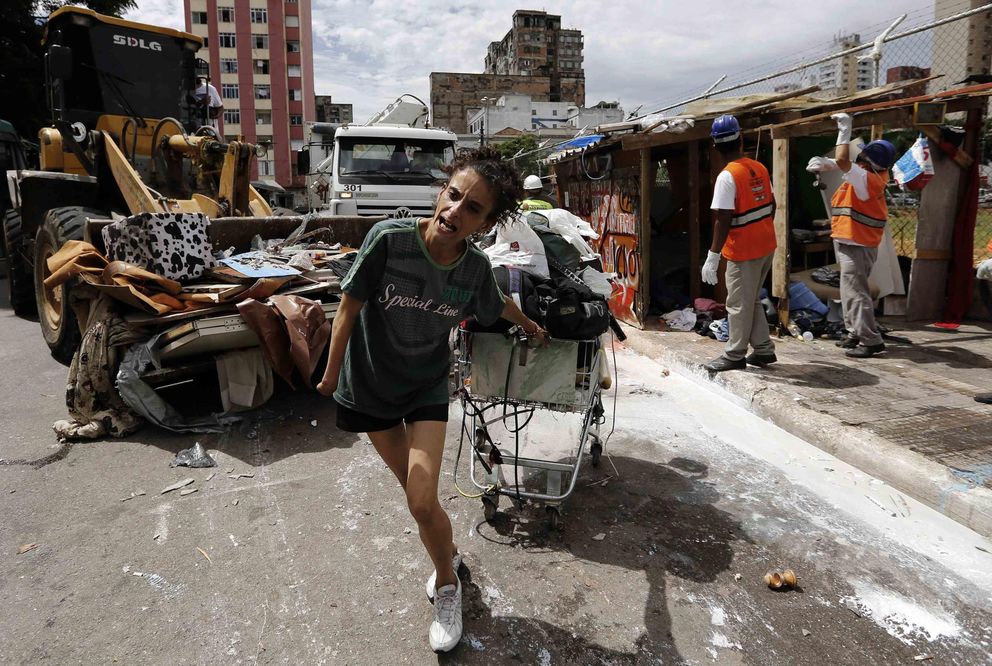 Una mujer se lleva sus pertenencias en un carrito tras el desalojo de su chabola en 