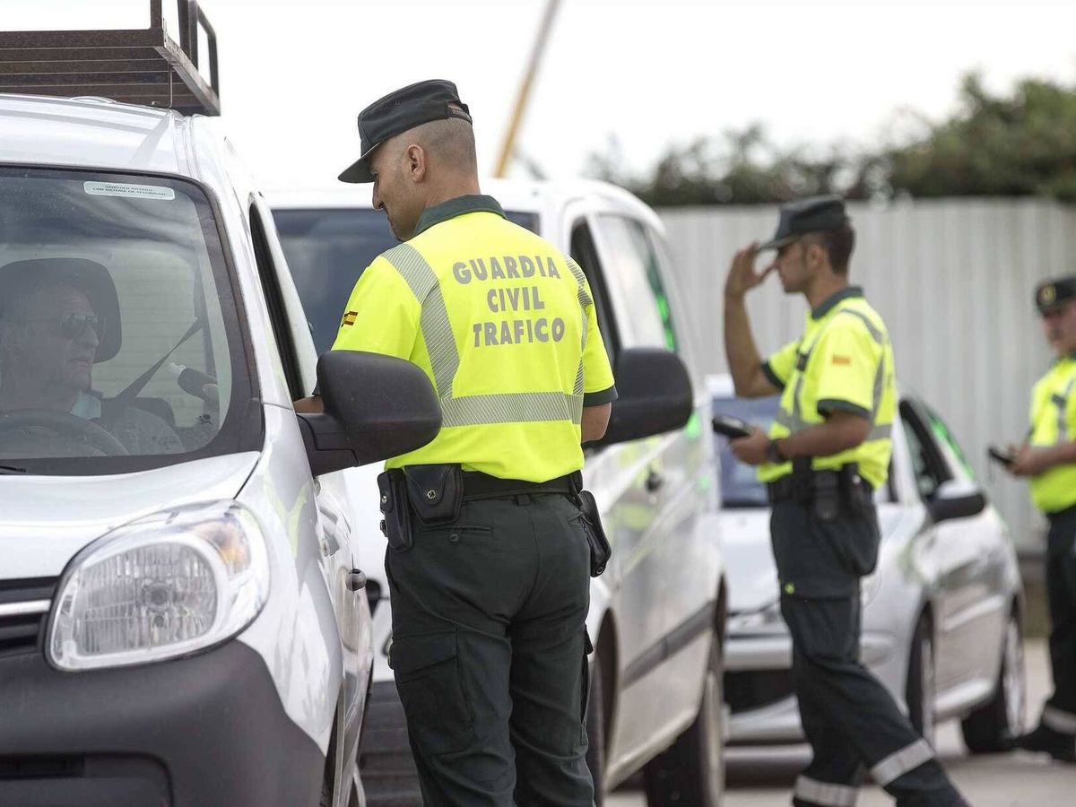 Foto: Agentes de la Guardia Civil de Tráfico inspeccionan la documentación de un grupo de conductores. 