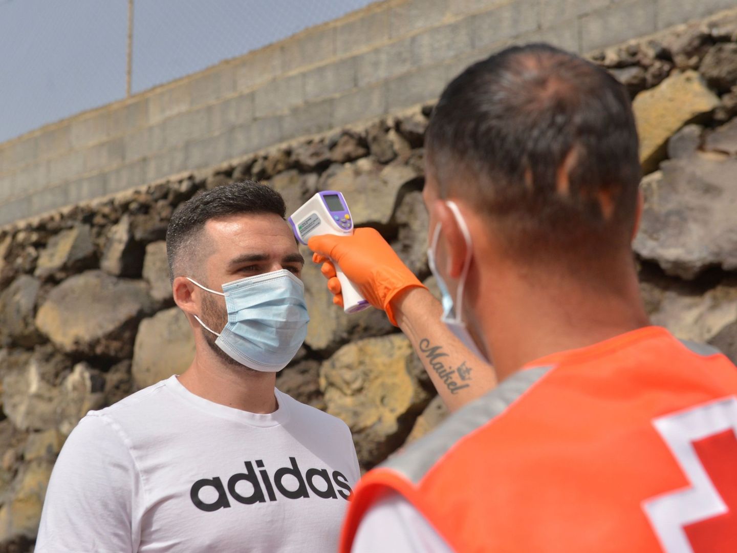 Un operario de la Cruz Roja toma la temperatura a un asistente a un partido de fútbol. (EFE)