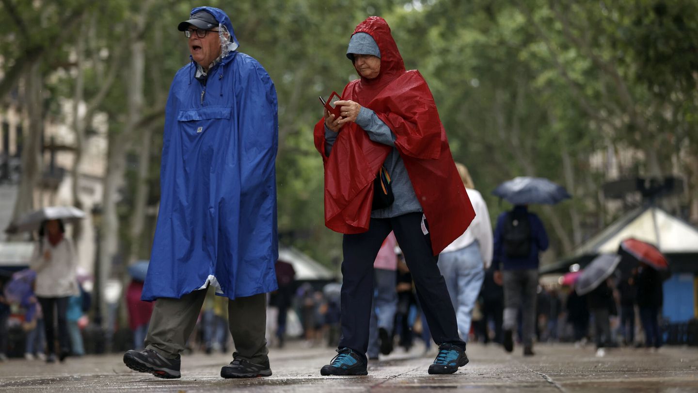 Dos personas se protegen de las intensas lluvias. (EFE)