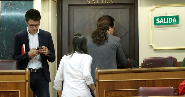 Foto: Íñigo Errejón consulta su móvil mientras Irene Montero y Pablo Iglesias abandonan el Congreso. (EFE)
