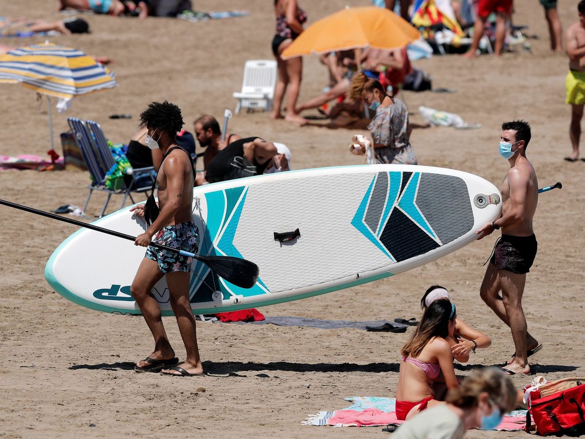Foto: Dos jóvenes transportan una tabla de 'paddle surf' en Valencia. (EFE)
